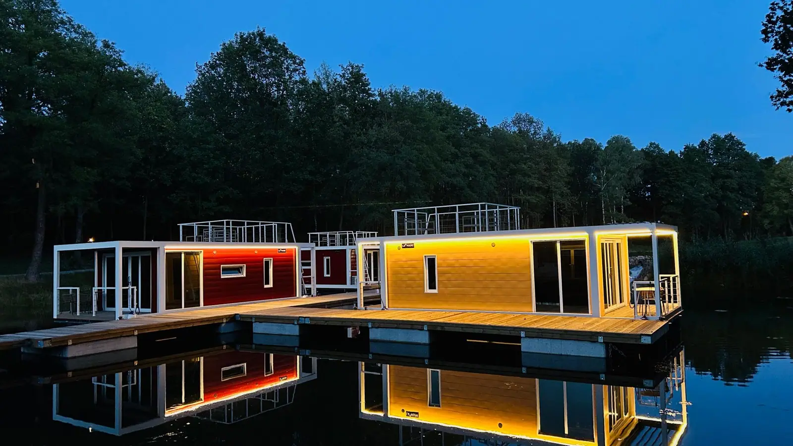 Houseboats éclairés au bord d’un lac au crépuscule